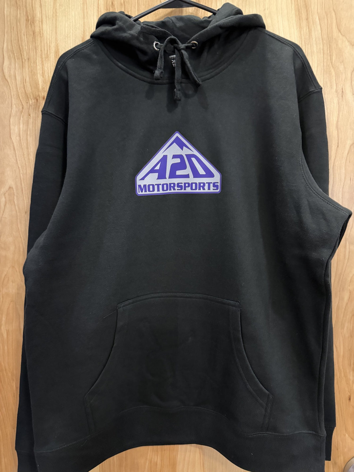 A2D Motorsports black hoodie with purple and white mountain logo, hanging