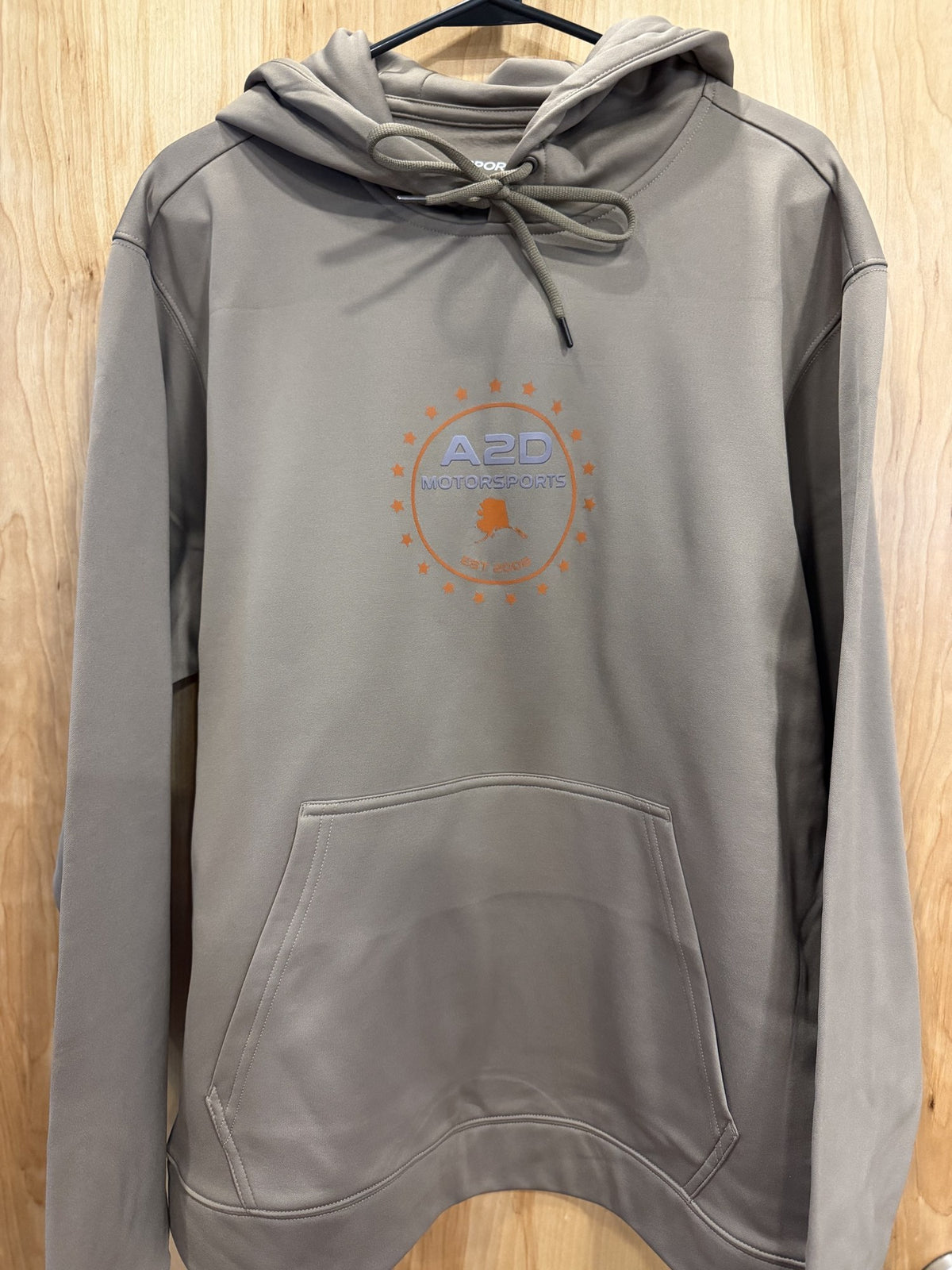 A2D Motorsports sand hoodie with orange Stars and State Alaska logo, hanging