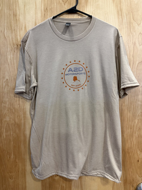 A2D Motorsports sand t-shirt with orange and grey Stars and State Alaska logo, hanging